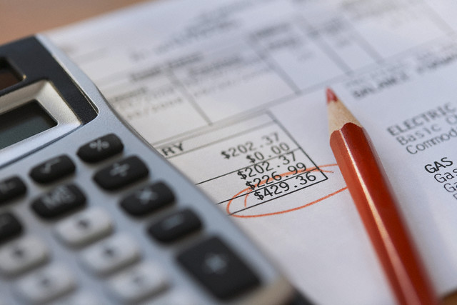 Calculator and pencil with bills --- Image by © Kate Kunz/Corbis